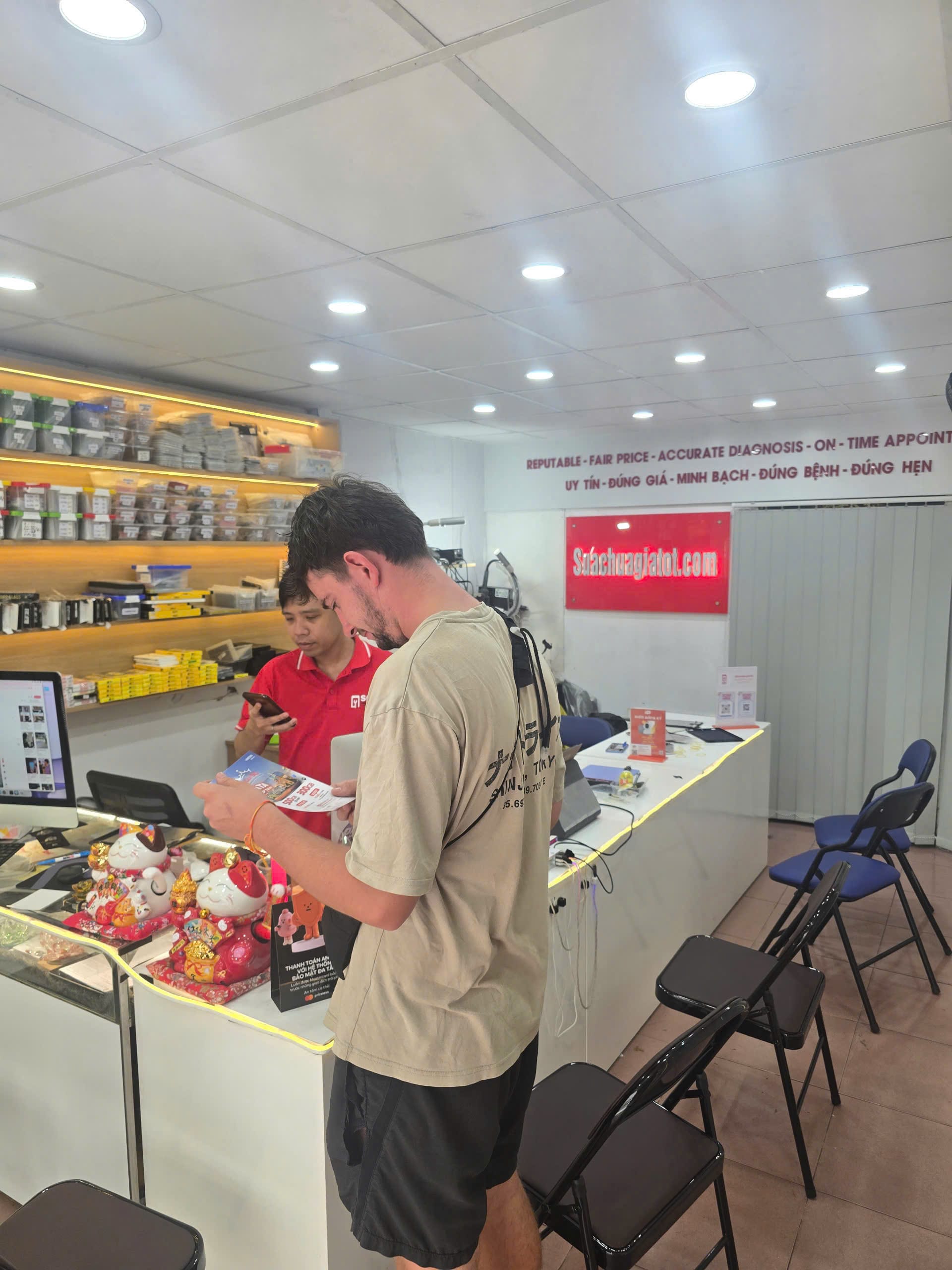 Kỹ thuật viên SCGT tư vấn khách hàng về dịch vụ thay kính lưng iPhone tại Quận 1 HCM